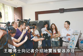 王暾博士向記者介紹地震報(bào)警器原理